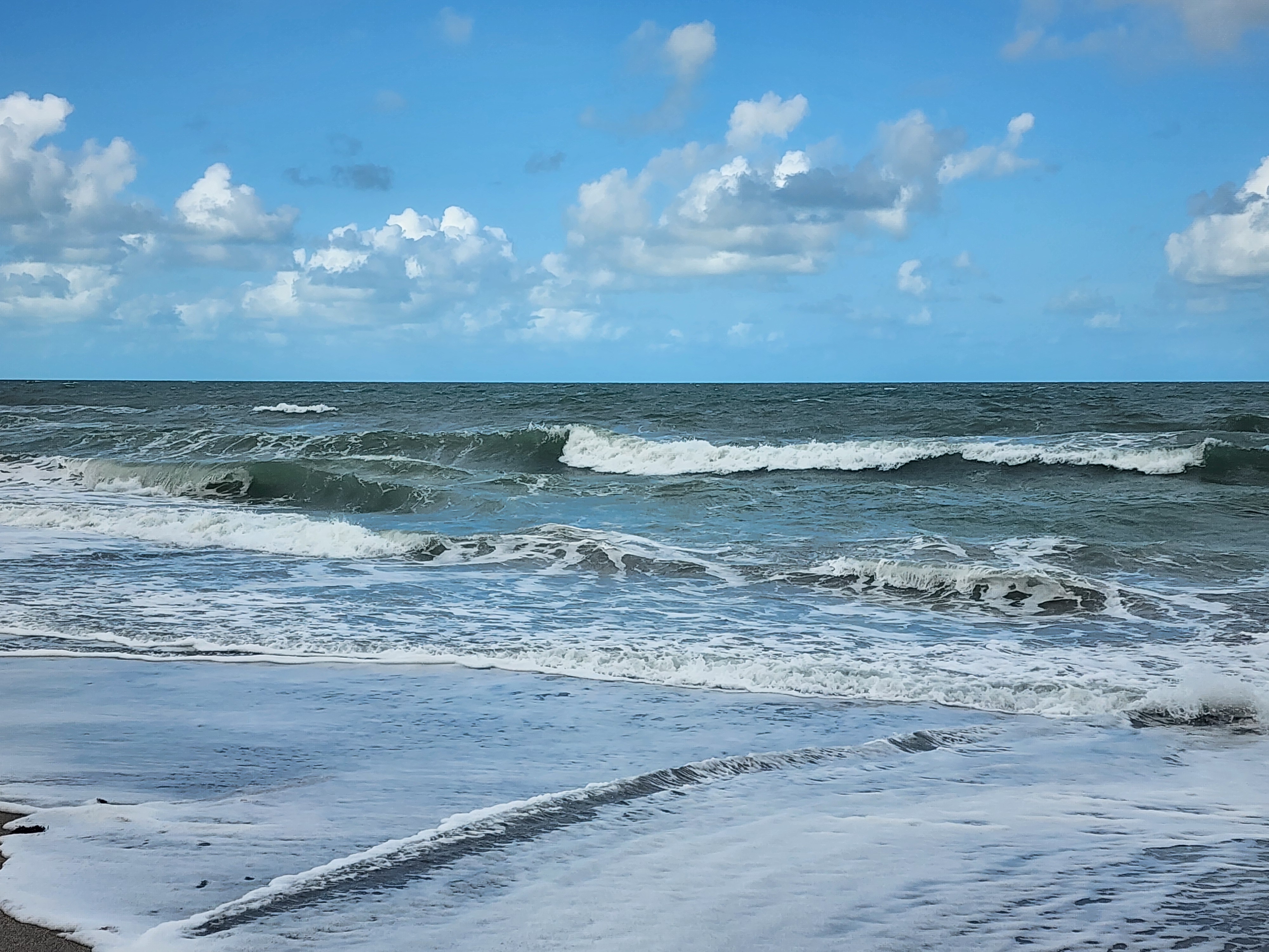 Nearly flat ocean with tiny wave at shoreline at 31st Street Cocoa Beach afternoon