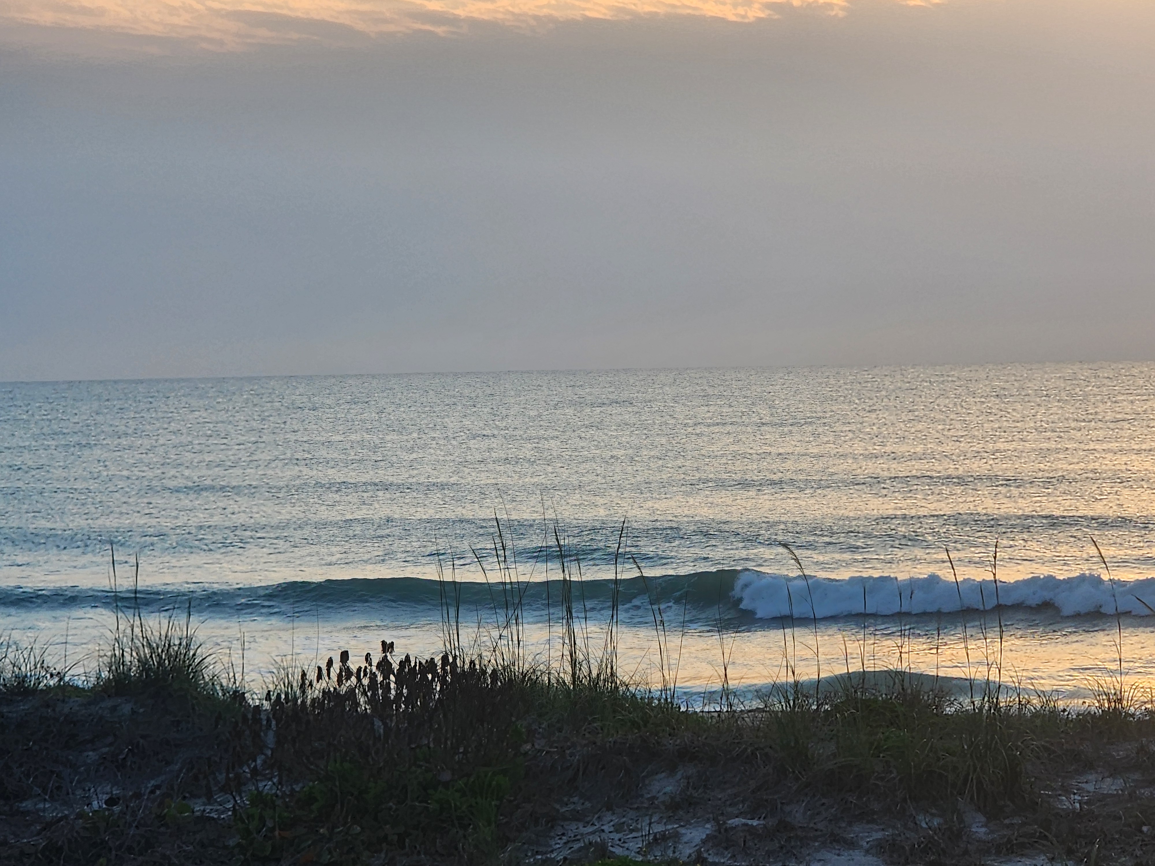 Surfer paddling into clean glassy lineup at Picnic Tables South Cocoa Beach April 30 morning session