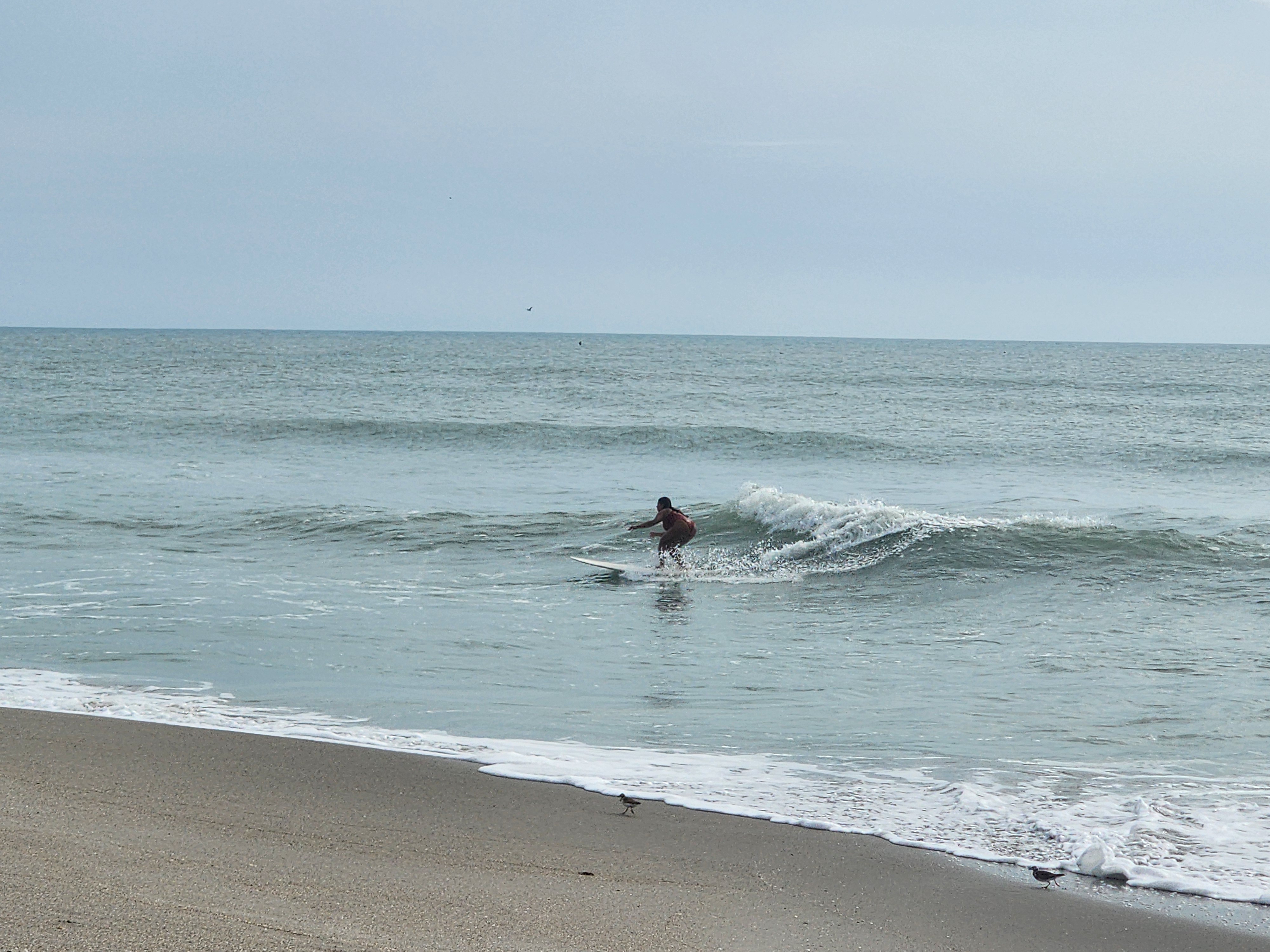 Surfer paddling out through clean afternoon lines at Picnic Tables South Cocoa Beach golden light