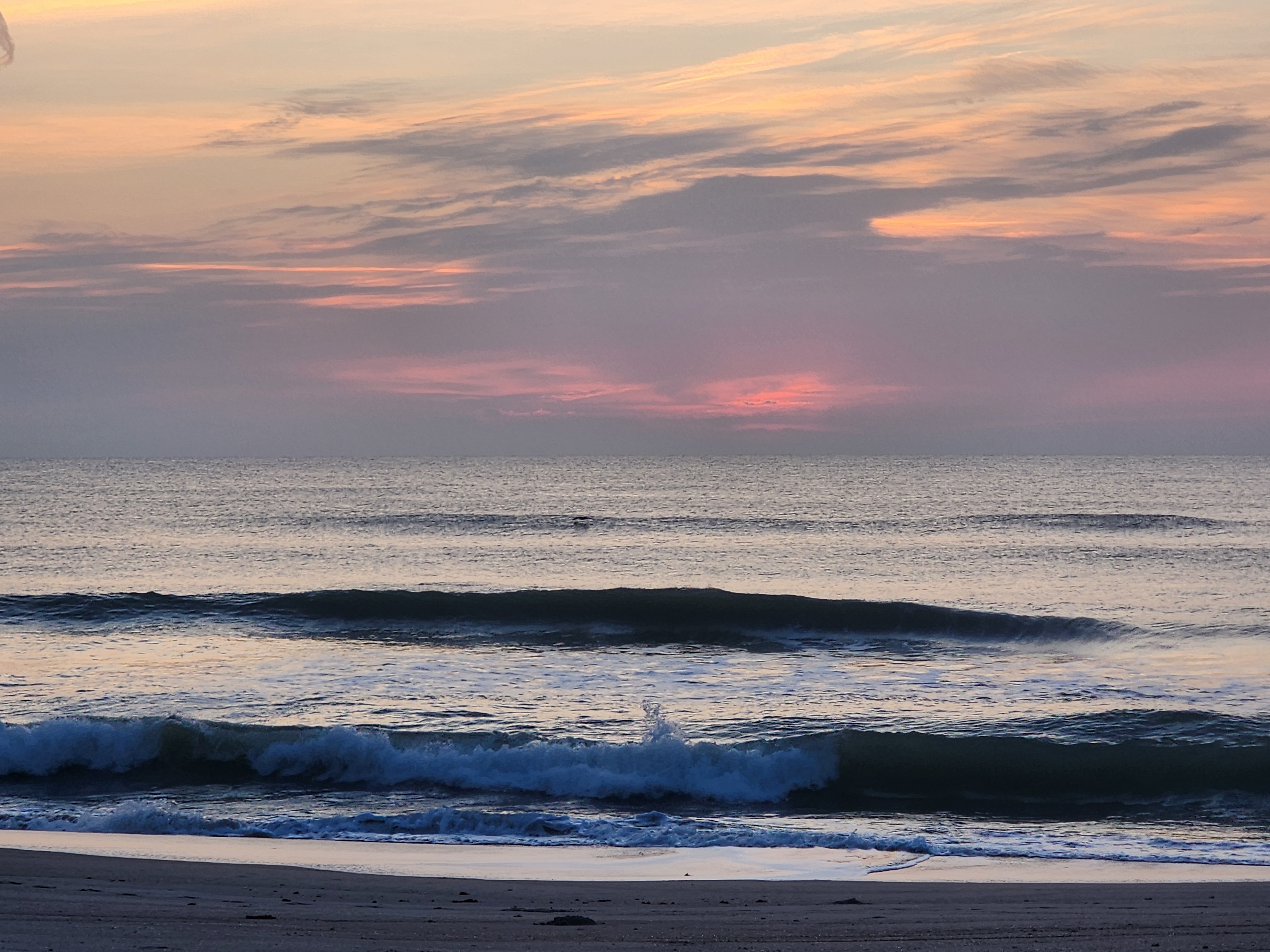 Surfer walking toward clean glassy lineup at Picnic Tables South Cocoa Beach Saturday morning