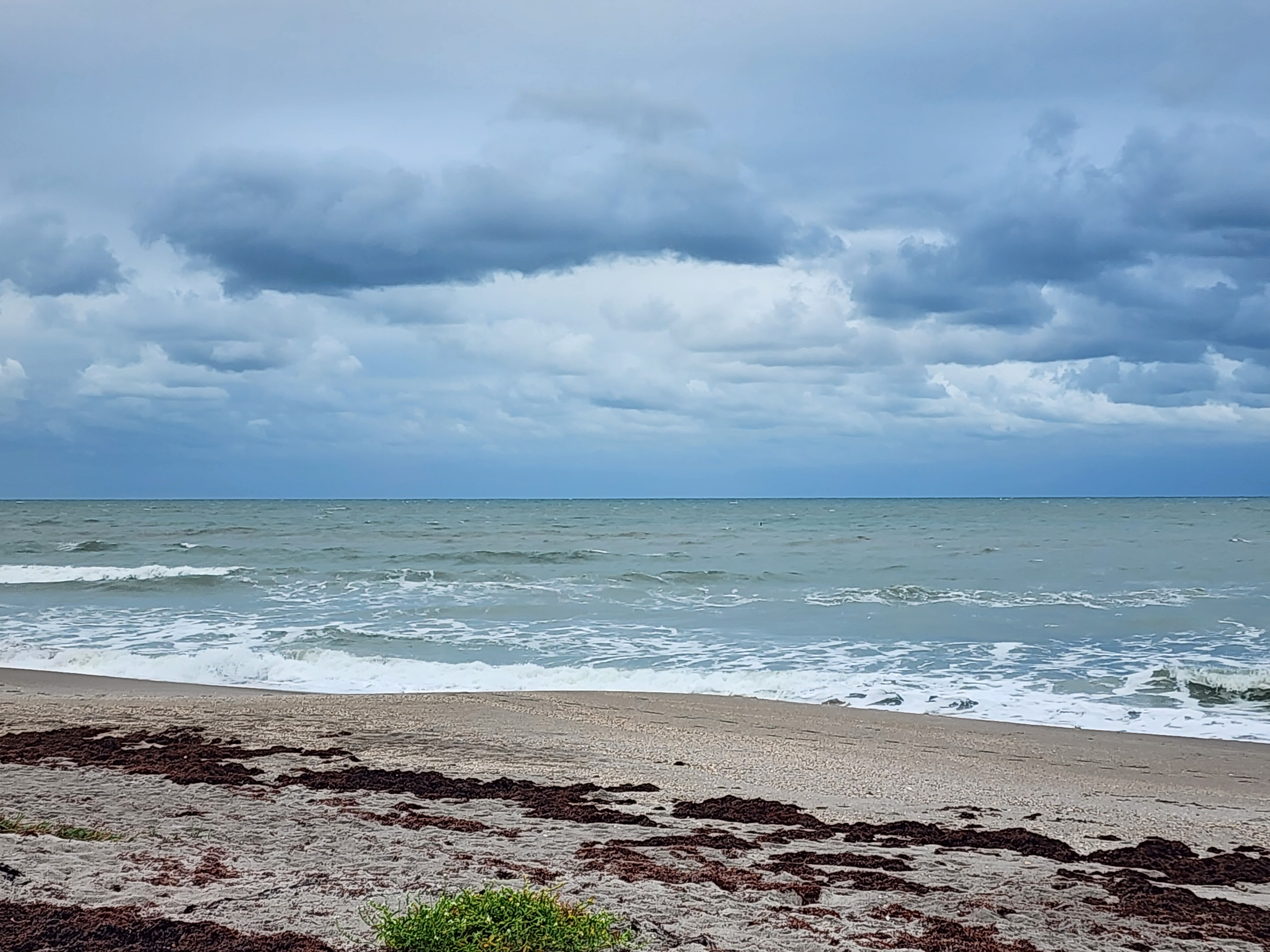 Small 1-2 foot wave rolling in on flat calm ocean at Picnic Tables South Cocoa Beach Sunday morning
