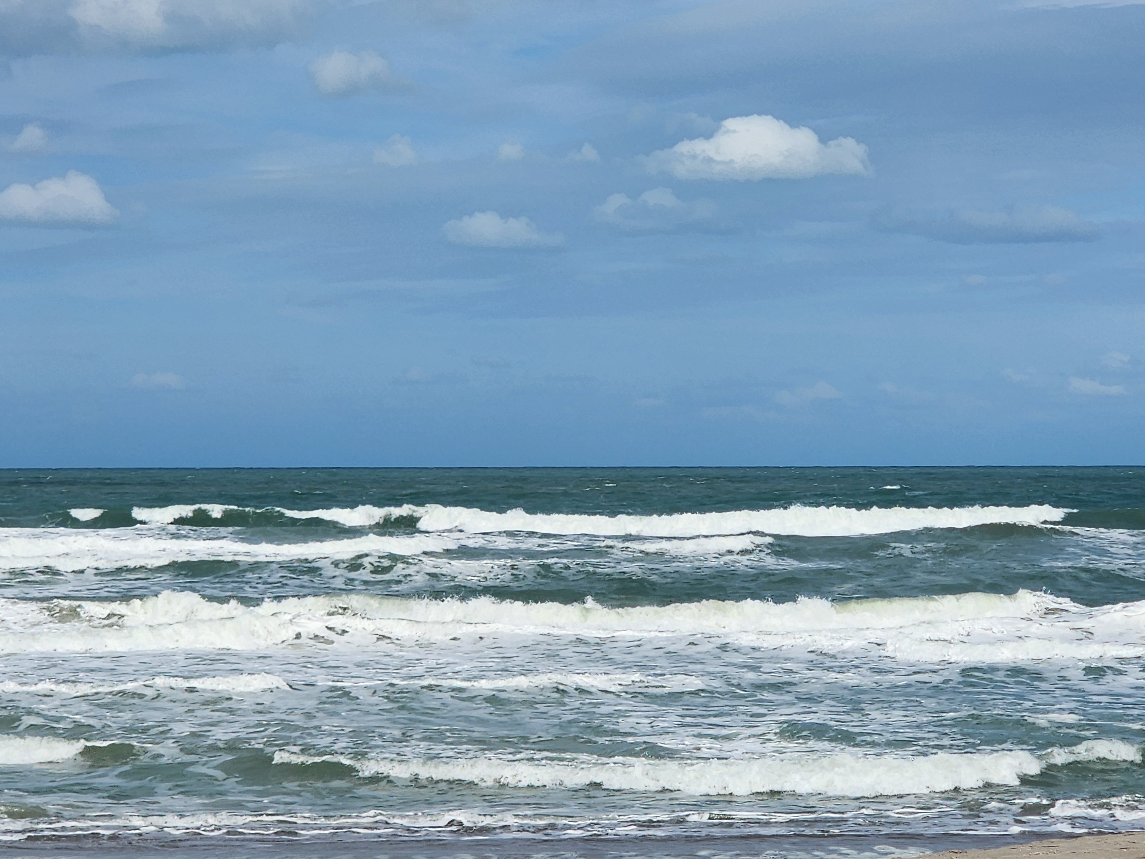 Wind-chopped 3-4 foot waves with spray blowing off the tops at Picnic Tables South Cocoa Beach