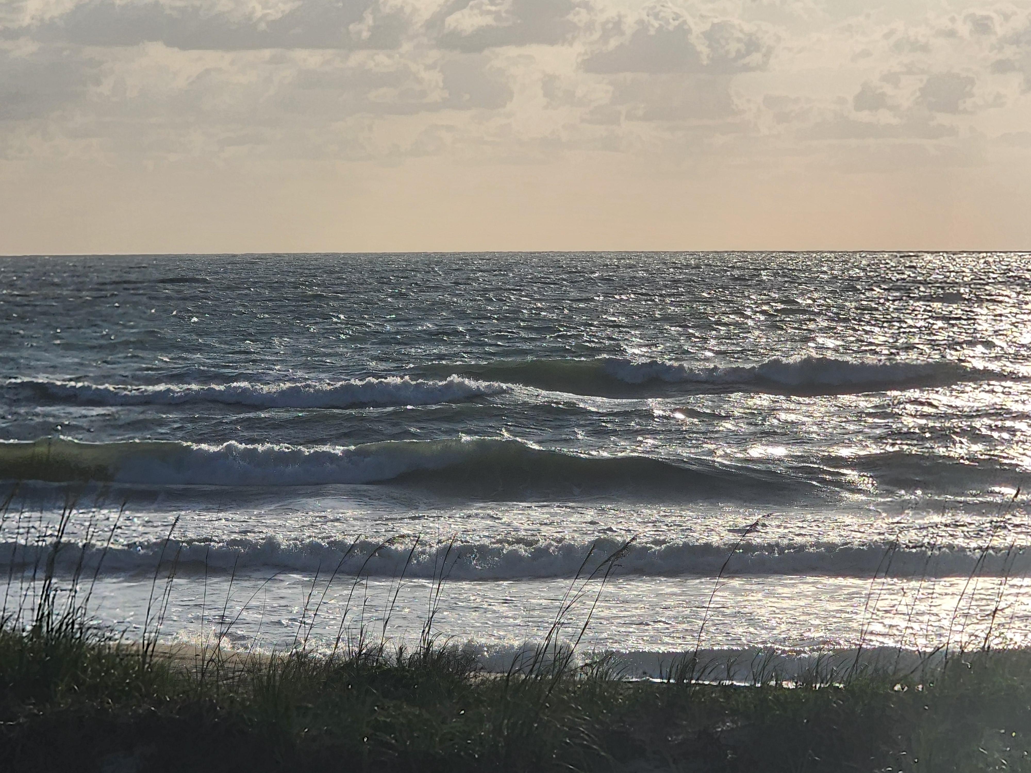 Choppy 2-3 foot surf with ENE onshore winds and sun glinting off the water at Picnic Tables South Cocoa Beach