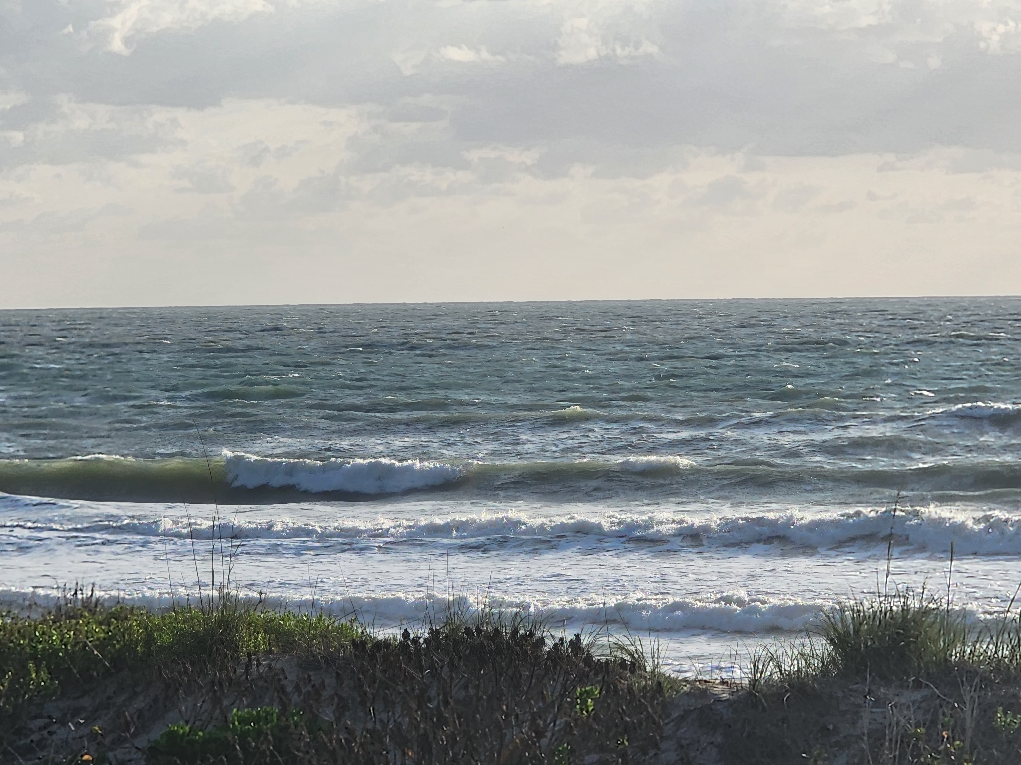 Messy 2-3 foot waves breaking with whitecaps and overcast skies at 31st Street Cocoa Beach morning