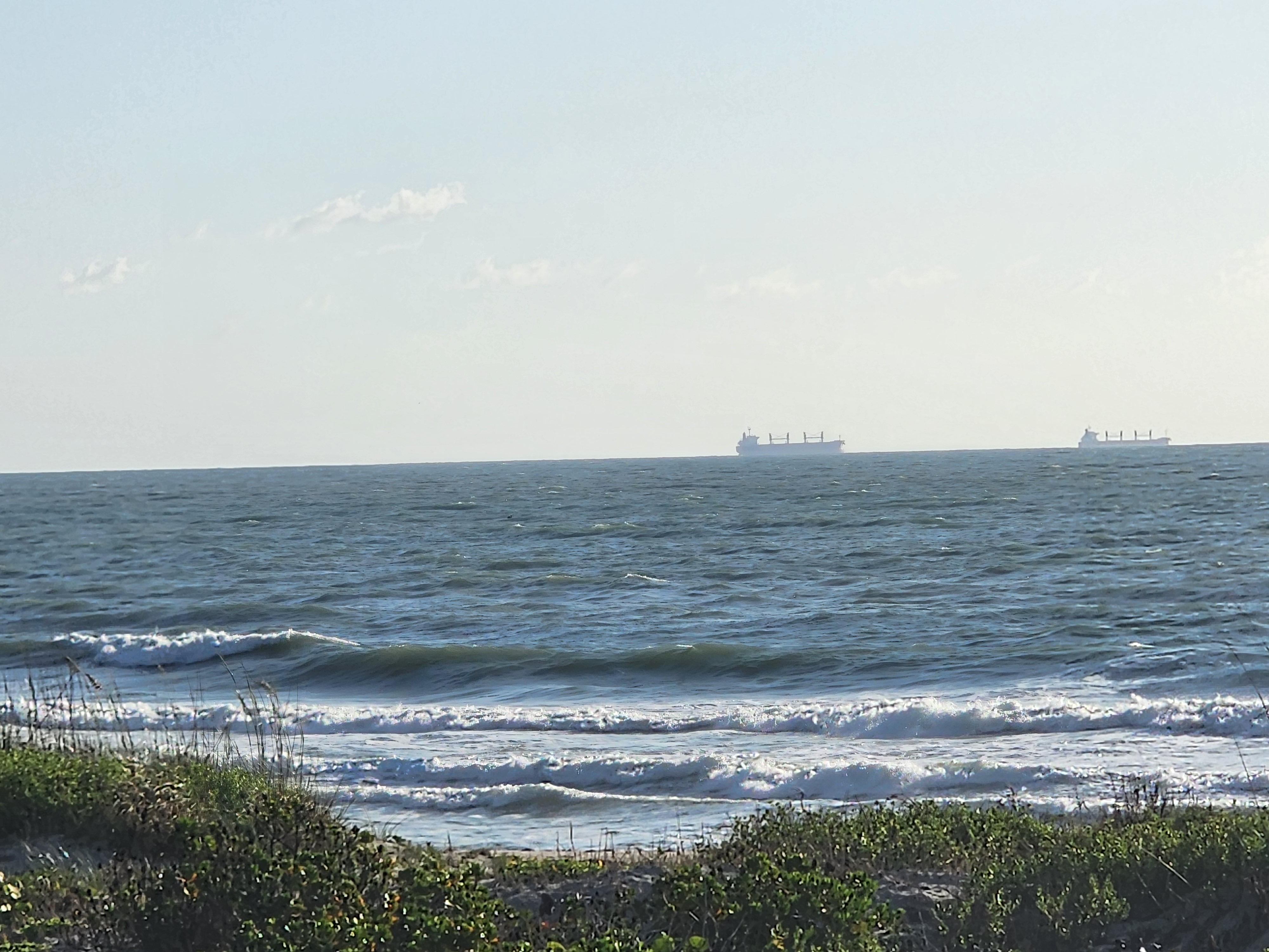 Choppy waves at Picnic Tables with two cargo ships anchored on the horizon near Port Canaveral