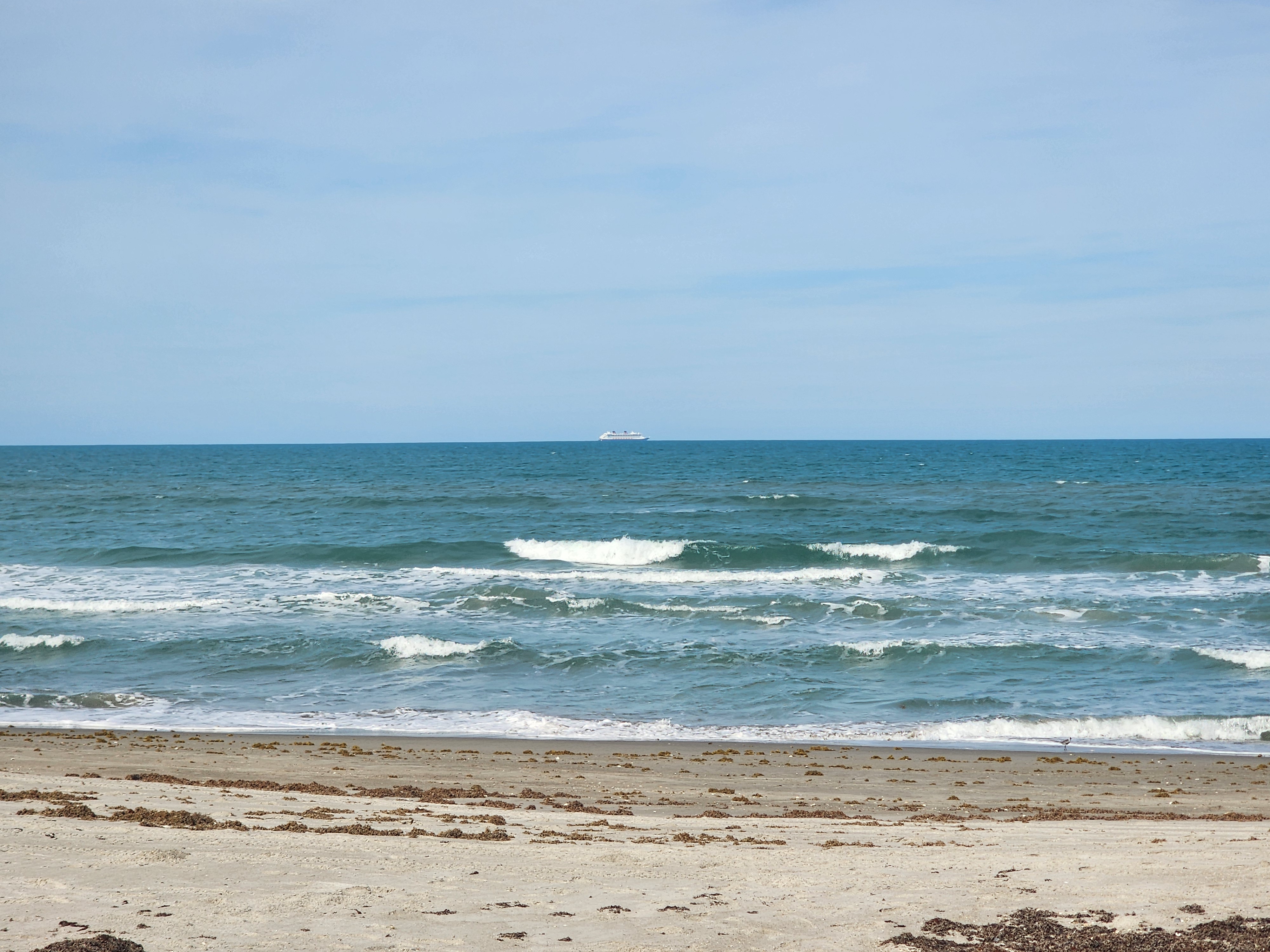 Aquamarine waves rolling in at Picnic Tables South Cocoa Beach with cruise ship heading into Port Canaveral
