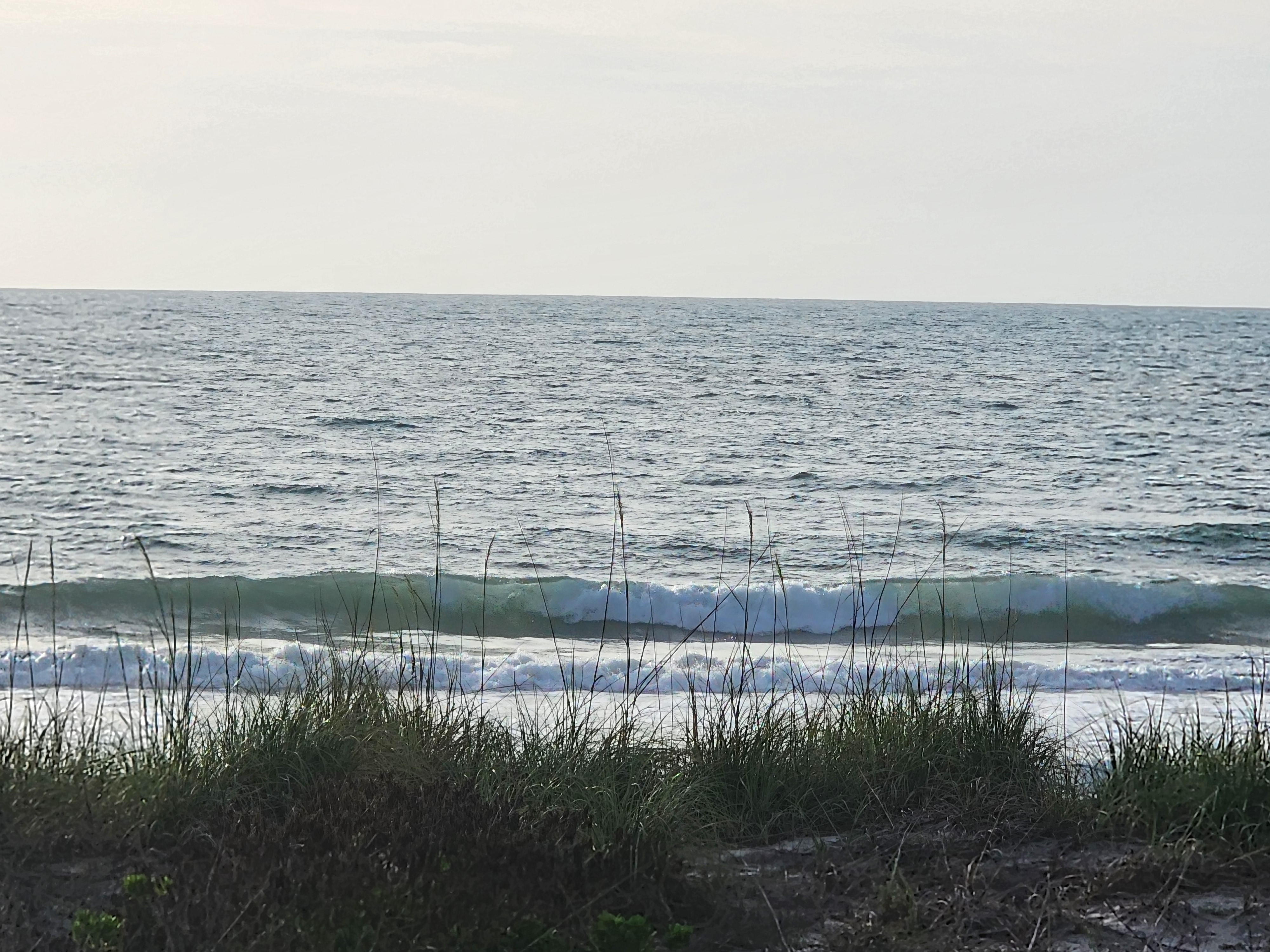 Clean 2-foot wave breaking through sea oats at Picnic Tables South Cocoa Beach morning May 6 2026