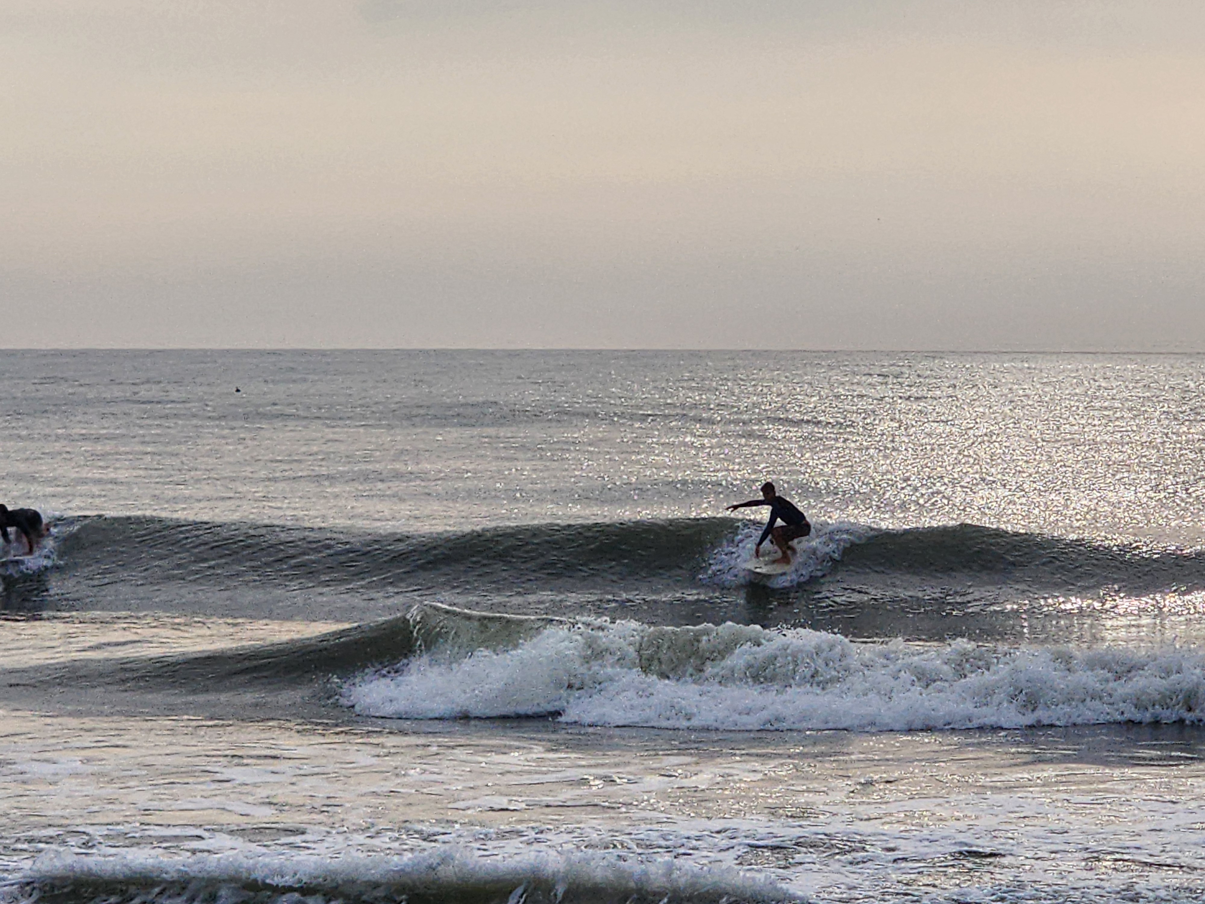 Surfer dropping in on a clean 2 foot wave with sun sparkling off the water at Picnic Tables South Cocoa Beach morning session