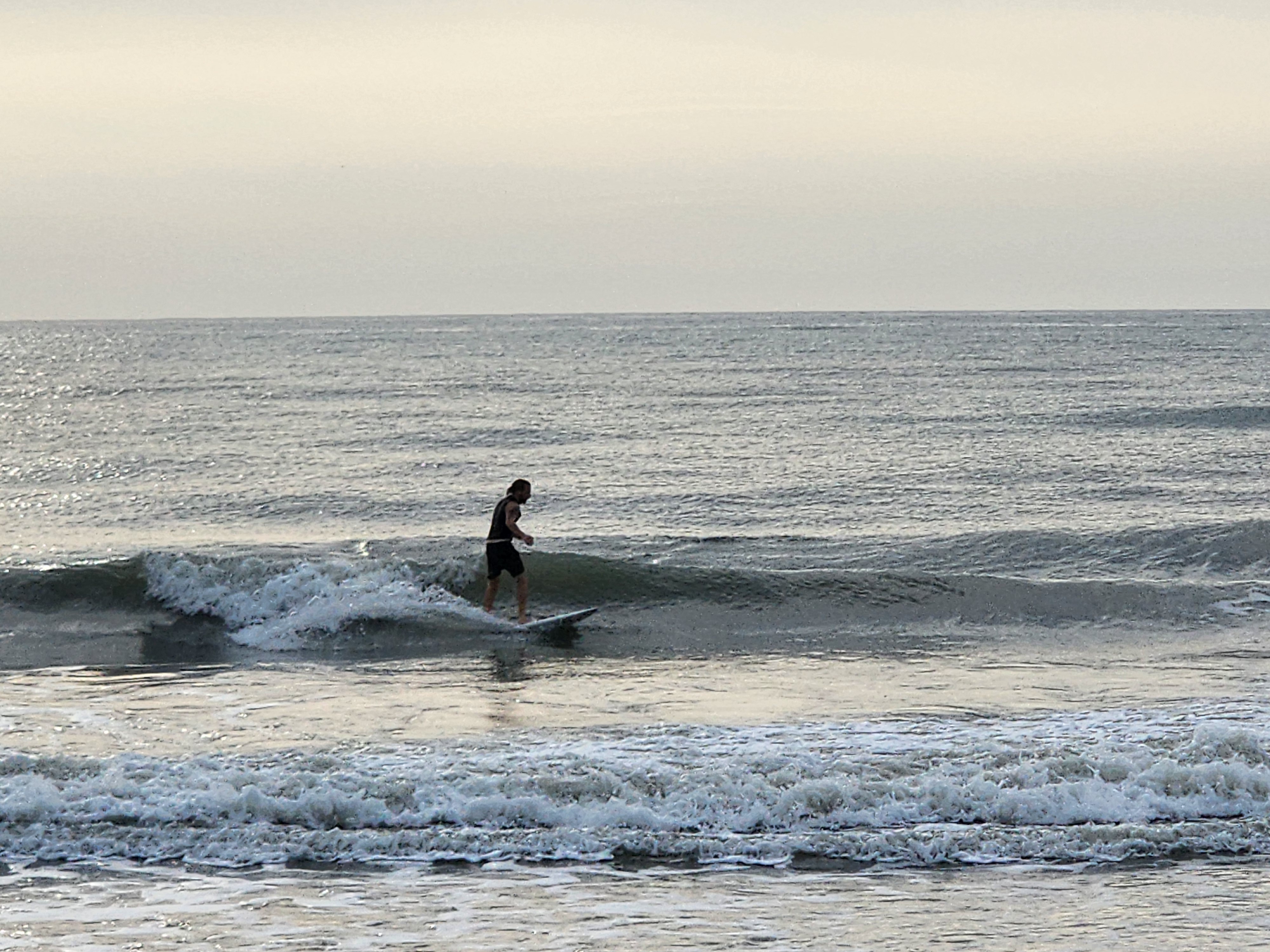 Longboarder cruising down the line on a clean 2 foot wave at Picnic Tables South Cocoa Beach popup swell May 10 2026