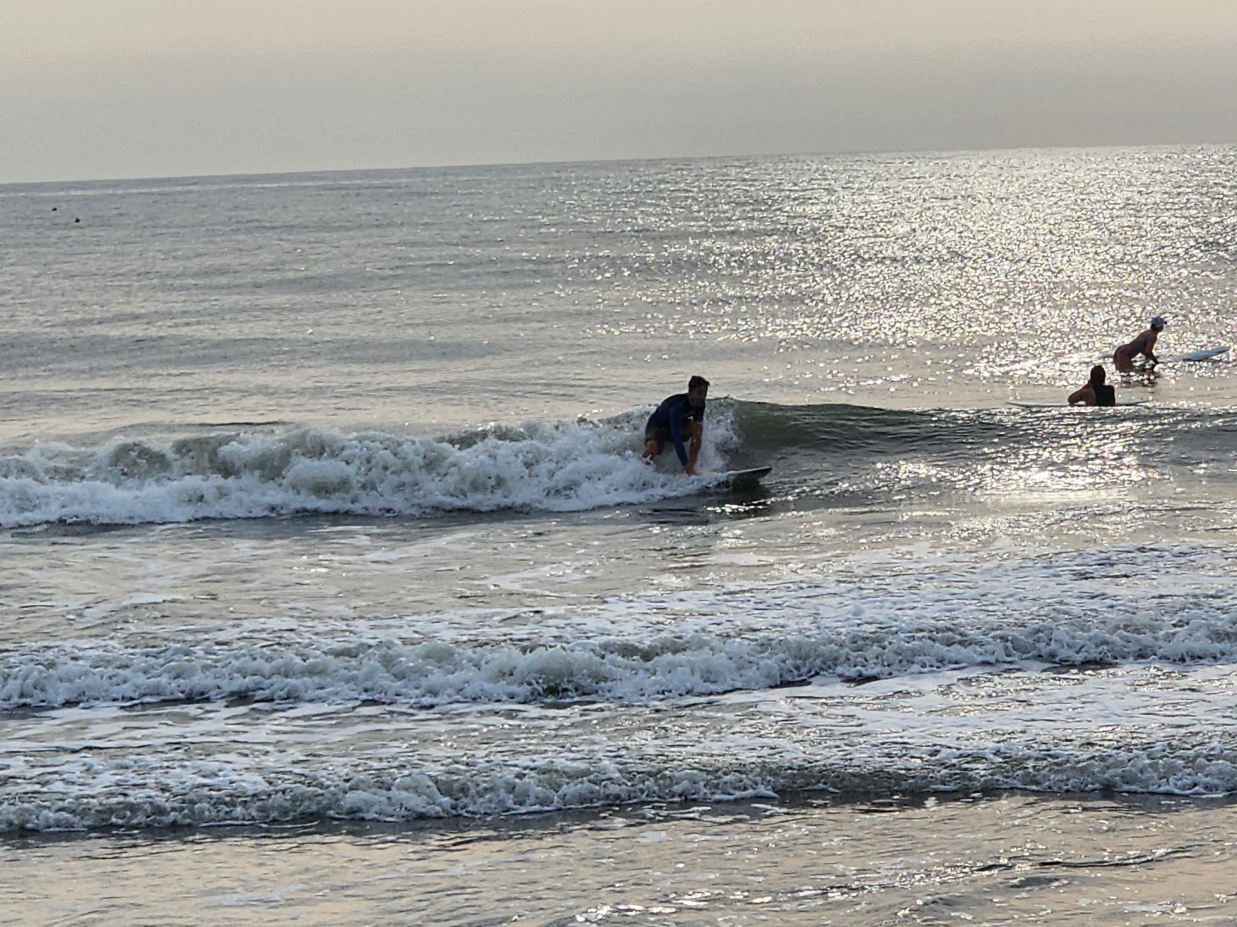 Surfer ripping a fun wave with other surfers paddling out in the background at Picnic Tables South Cocoa Beach lowtide sandbars Sunday morning