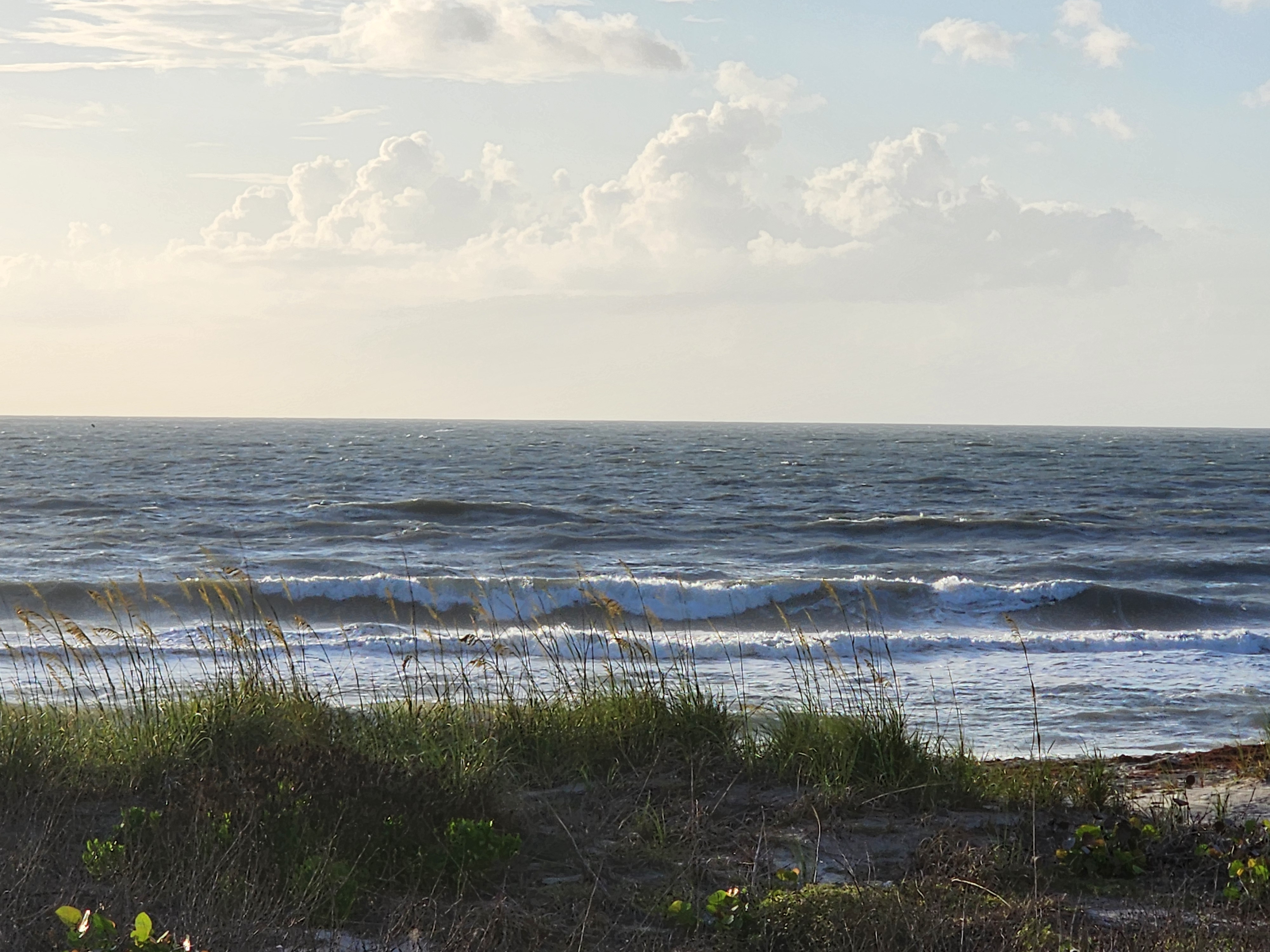 Choppy 2-4 foot wind swell with morning sun lighting up waves through sea oats at South Cocoa Beach Memorial Day 2026