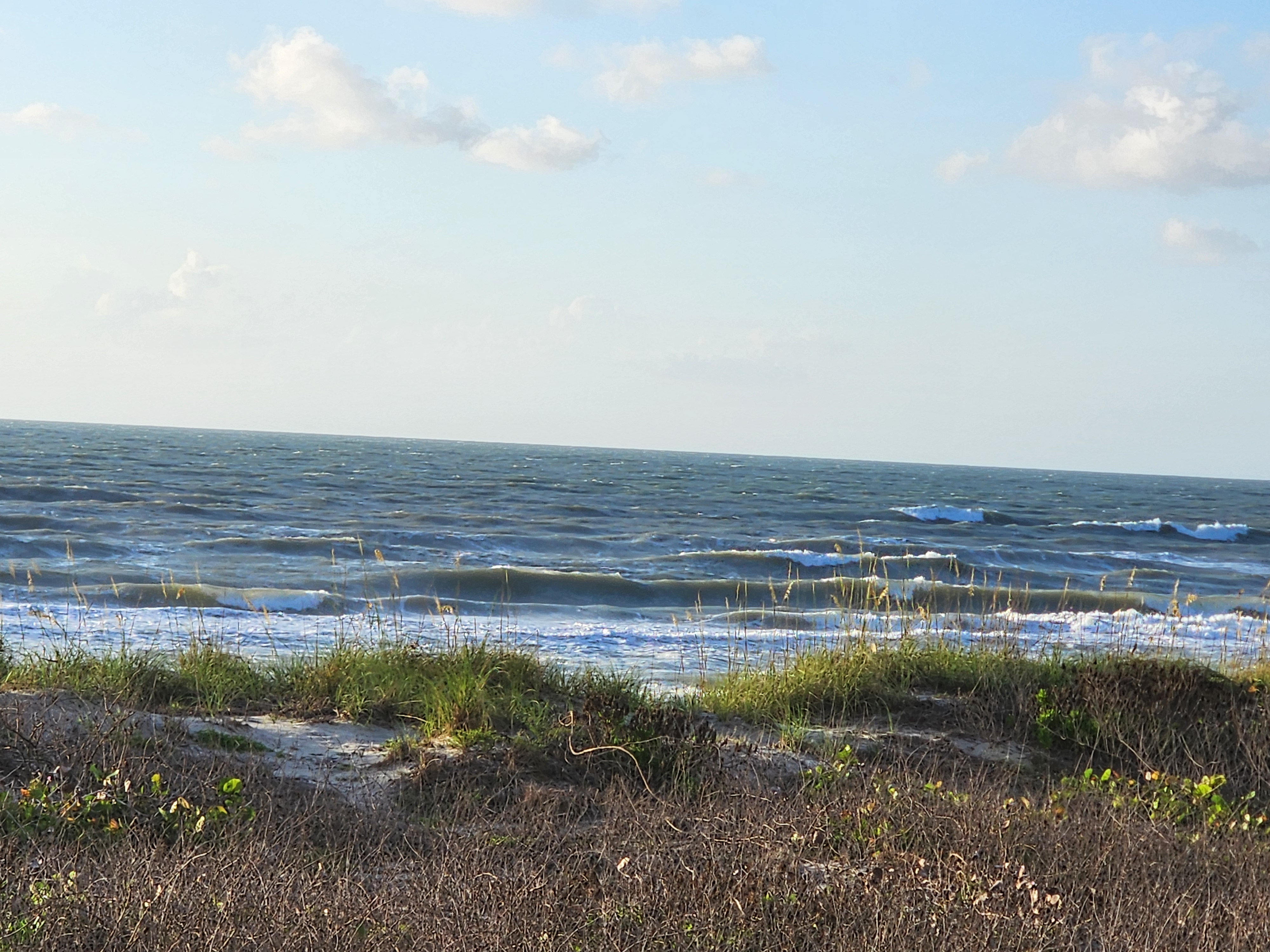 Wind-textured lines stacking up over dunes with scattered clouds at Picnic Tables Cocoa Beach