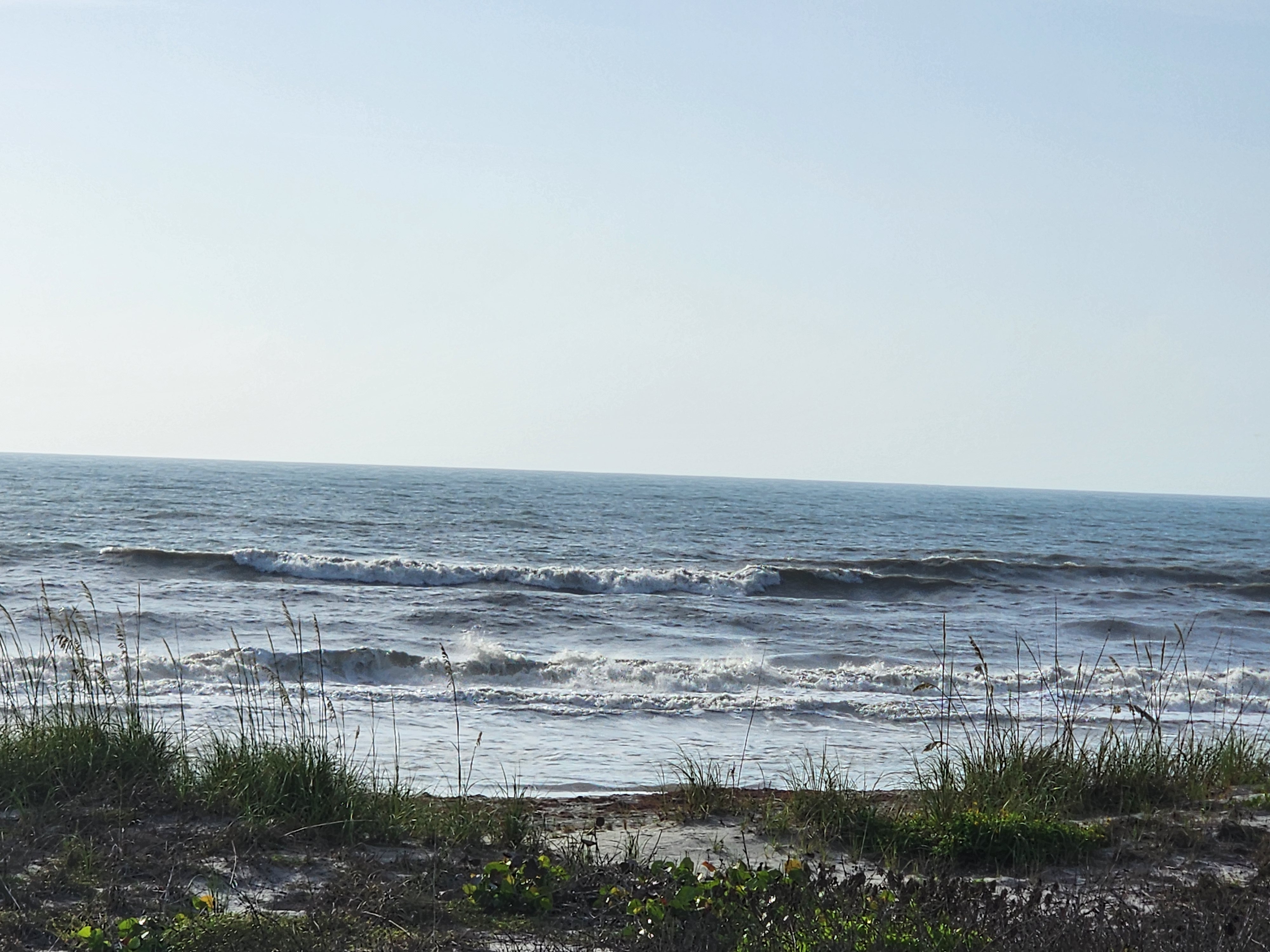 Clean lines stacking through onshore chop with sea oats and dune grass at Picnic Tables Cocoa Beach