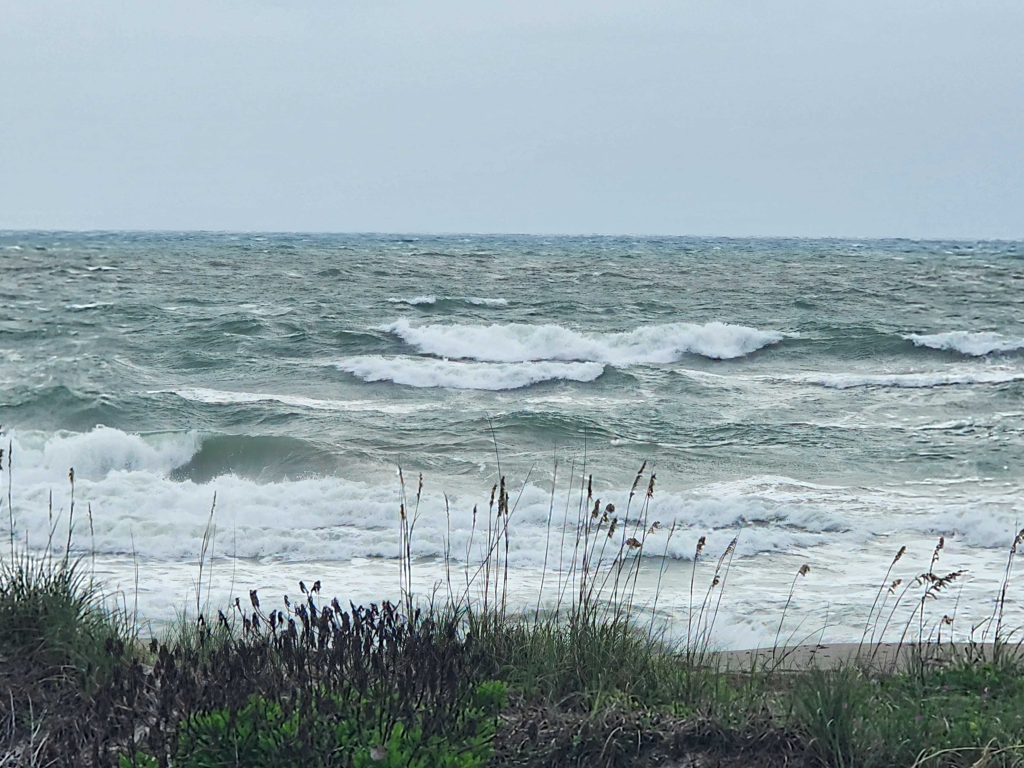 Heavy whitewater and choppy wind swell crashing near shore with sea oats bending in 20-30 mph NE winds South Cocoa Beach