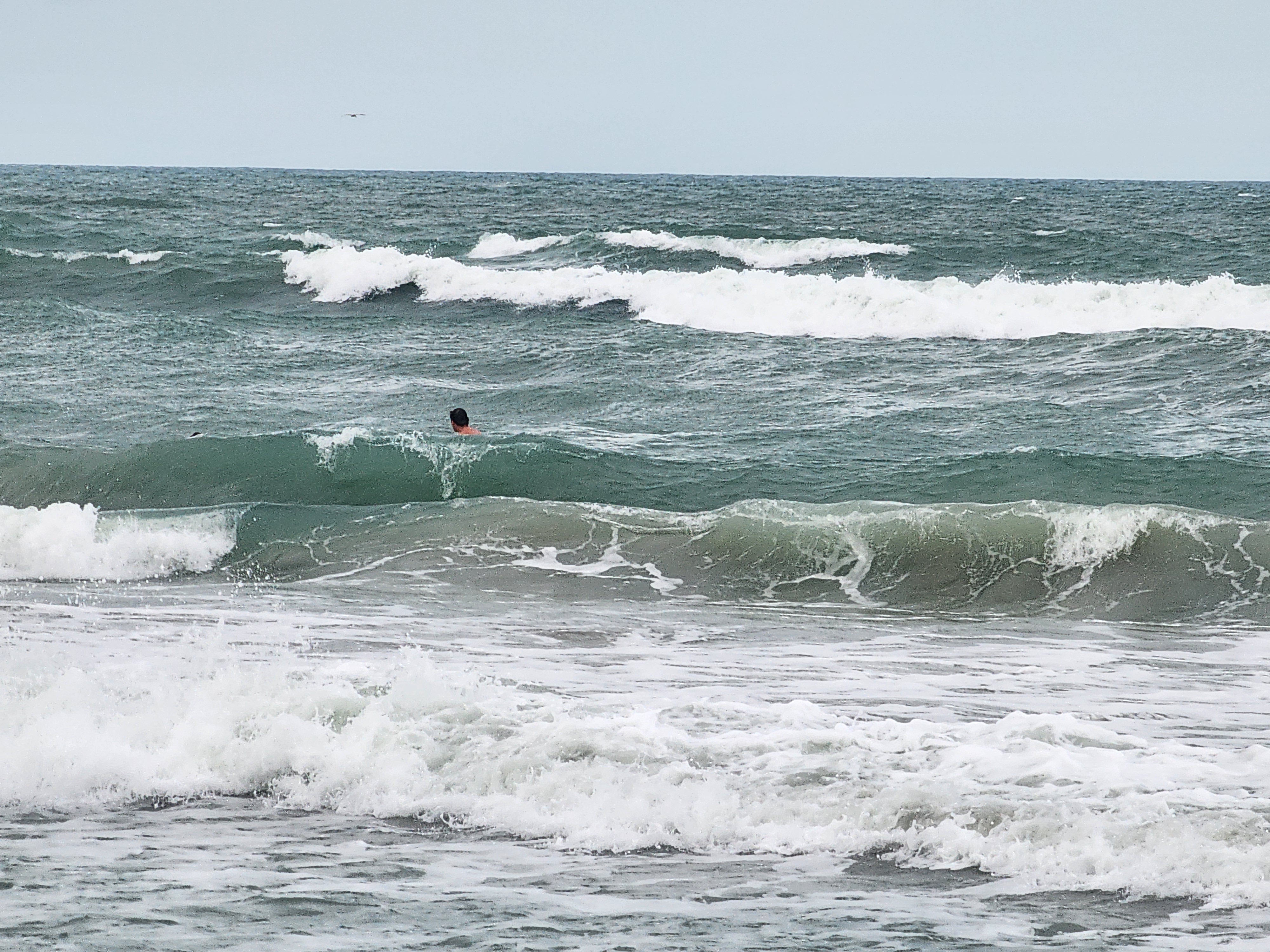 Bodysurfer diving into solid green wave face with whitecaps and stacked lines at Picnic Tables Cocoa Beach June swell