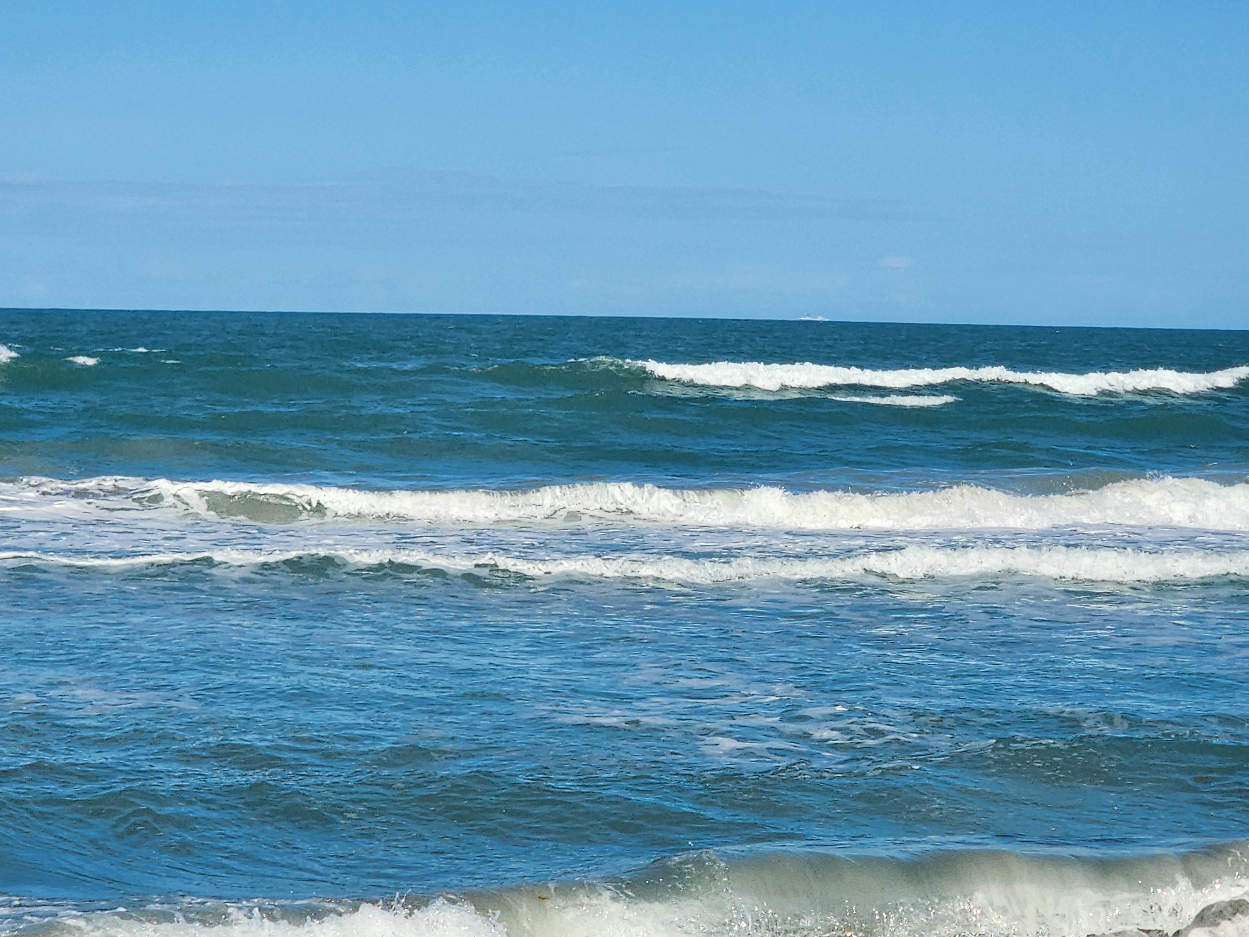 Stacked 3-4 foot waves breaking in bright blue water with onshore chop at South Cocoa Beach afternoon June 5 2026
