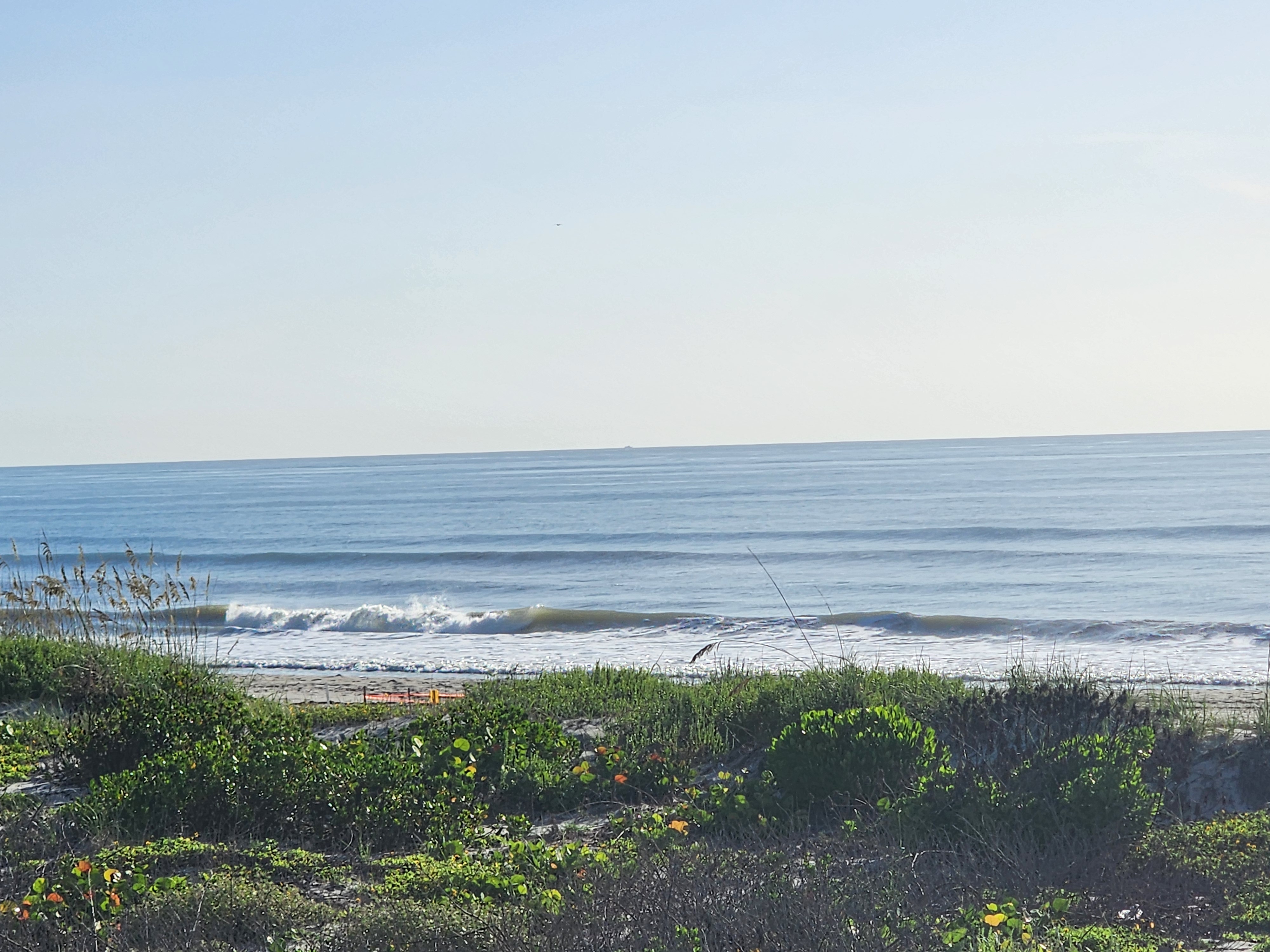Glassy shoulder-high waves breaking under clear blue sky, South Cocoa Beach, July 2026