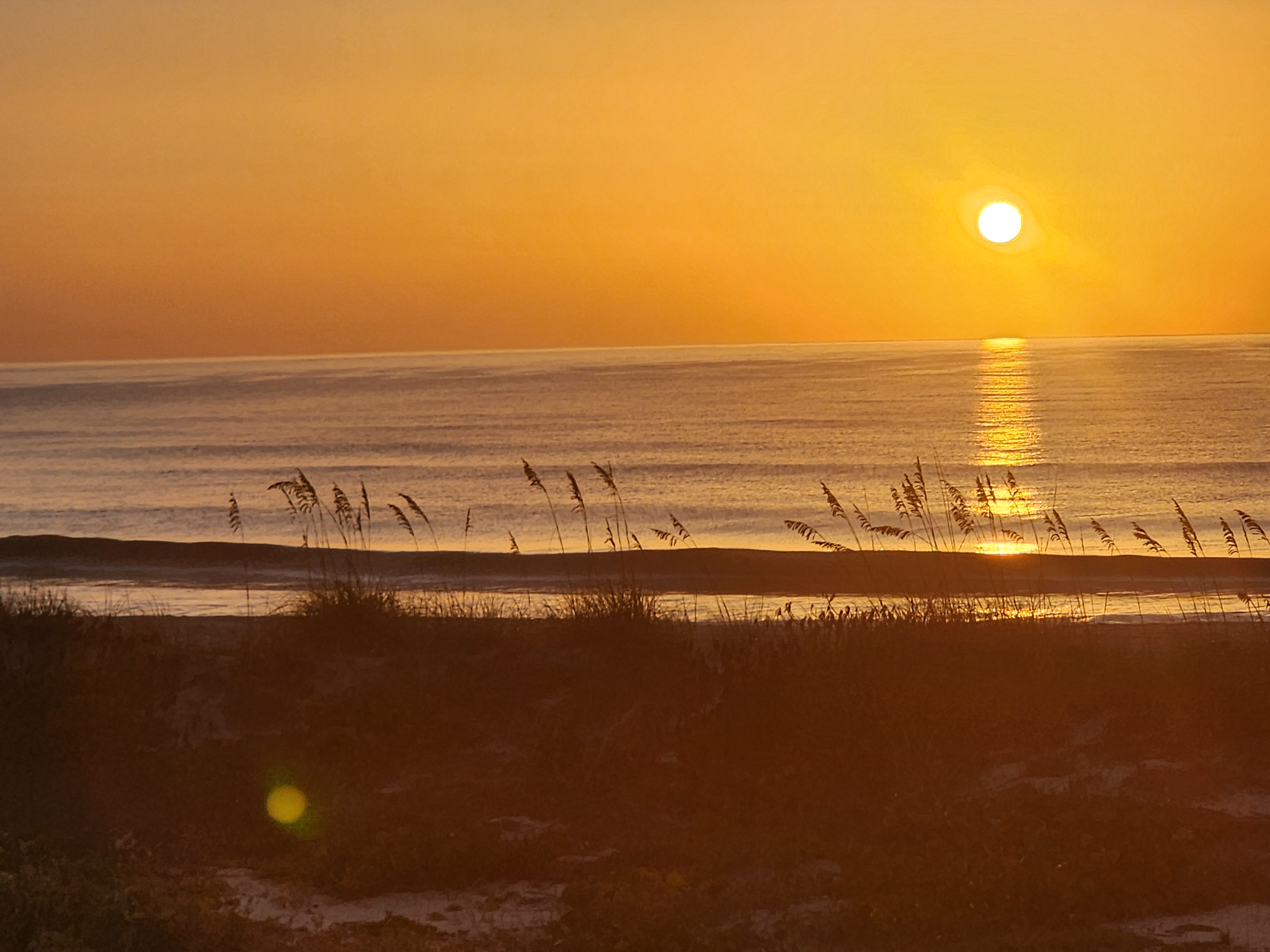 Sun rising over the horizon casting a golden glow on the water, South Cocoa Beach, July 2026