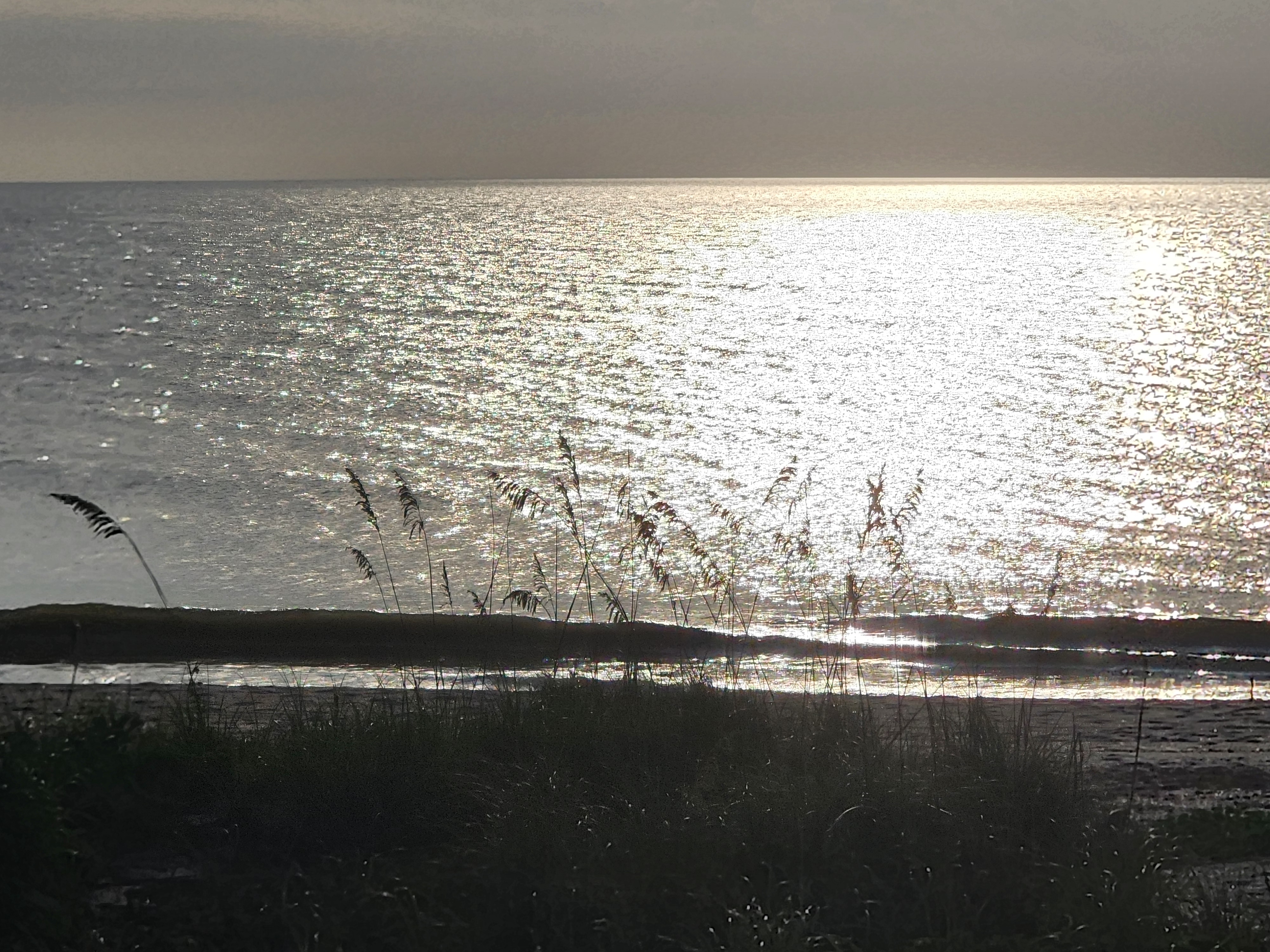 Sun glare over calm, flat water at high tide, South Cocoa Beach