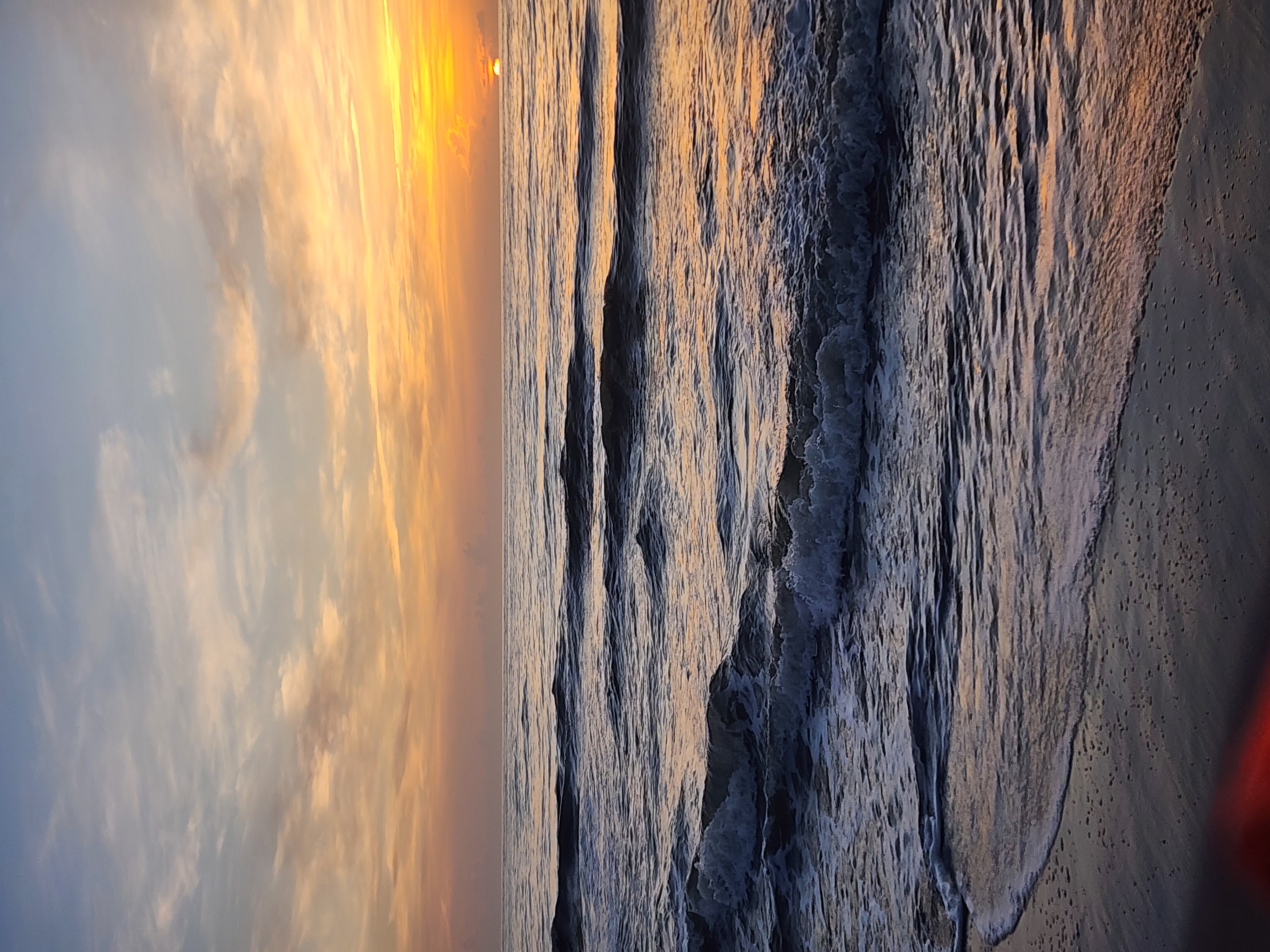 Small clean set breaking in the shorebreak at sunrise with the sun low on the horizon and wet sand in the foreground at 32nd Street