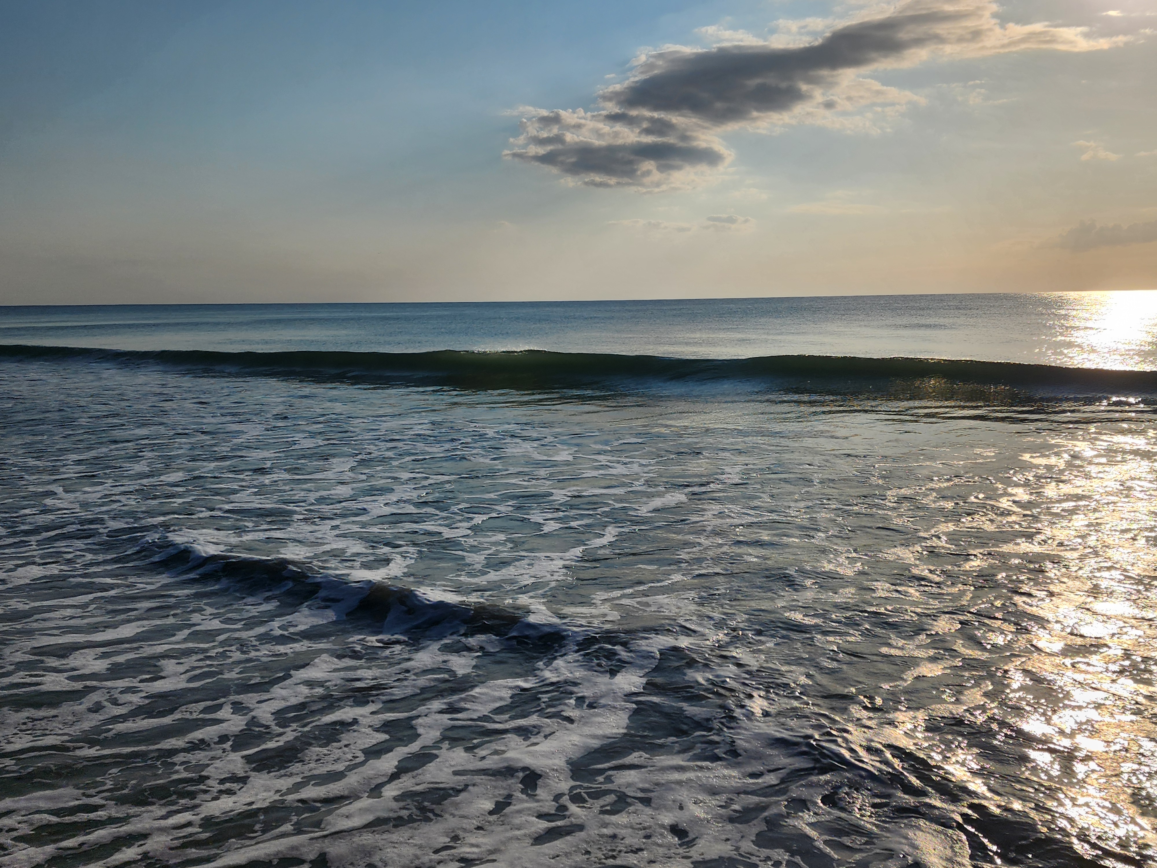 Small clean wave breaking under a partly cloudy sky, South Cocoa Beach