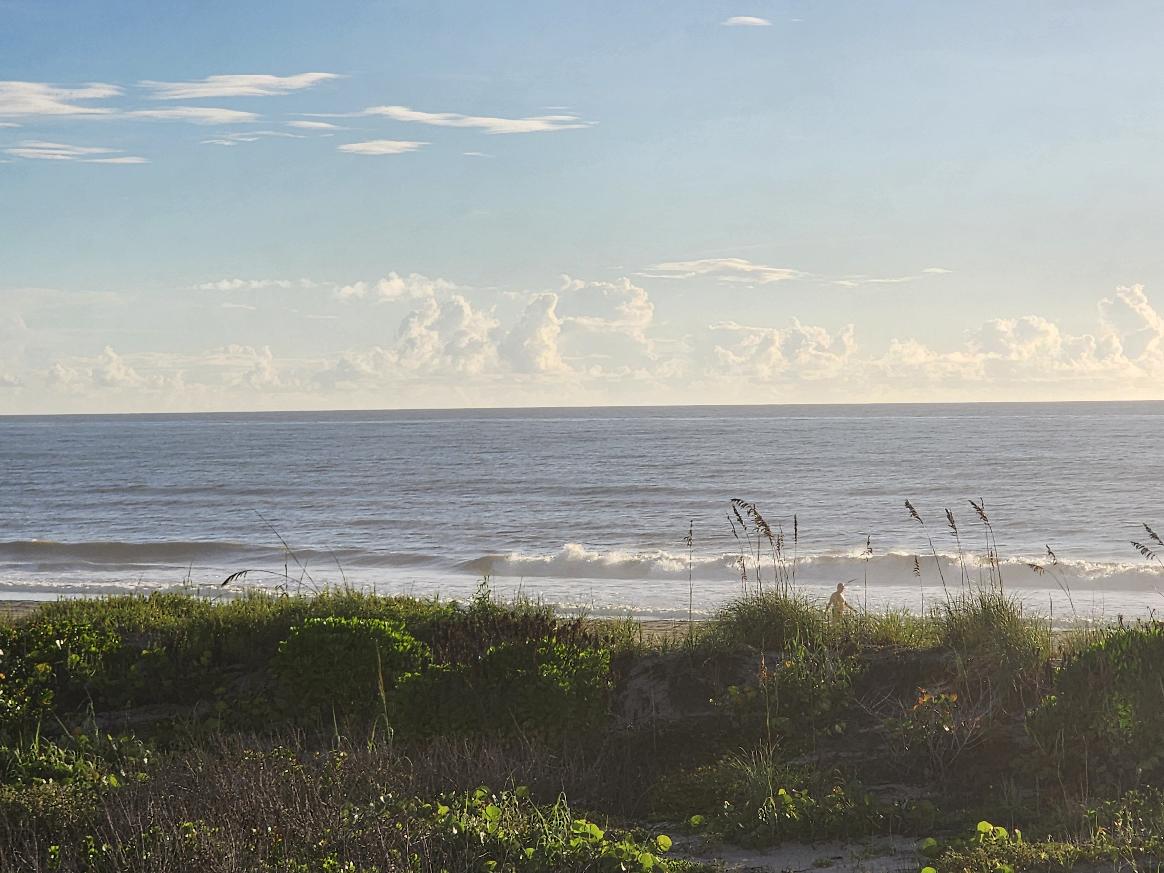 Morning walker down at the waterline with wind bump on the wave faces, South Cocoa Beach