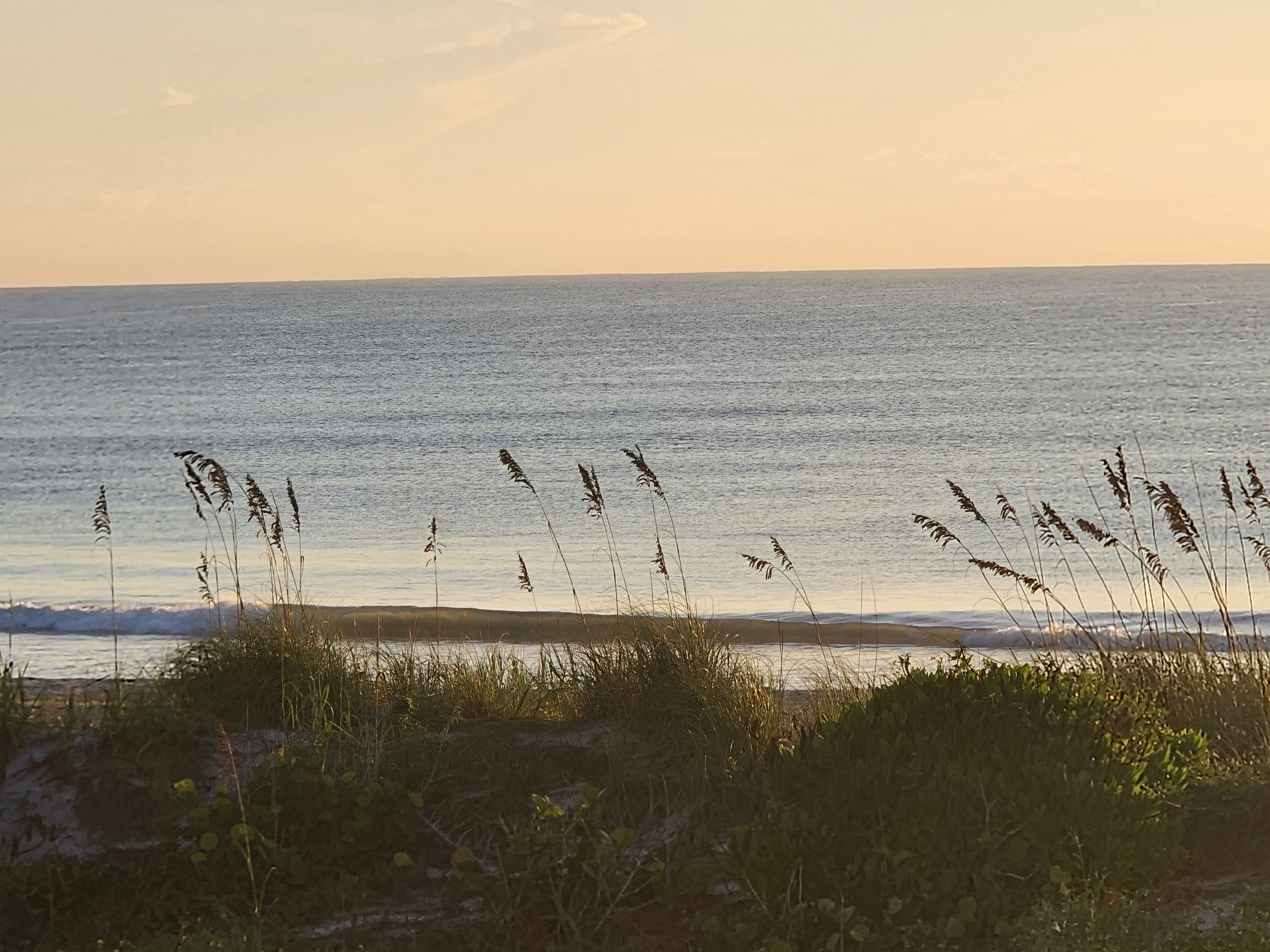 Long glassy swell line standing up under a peach and gold sky at 32nd Street, South Cocoa Beach, September 2026