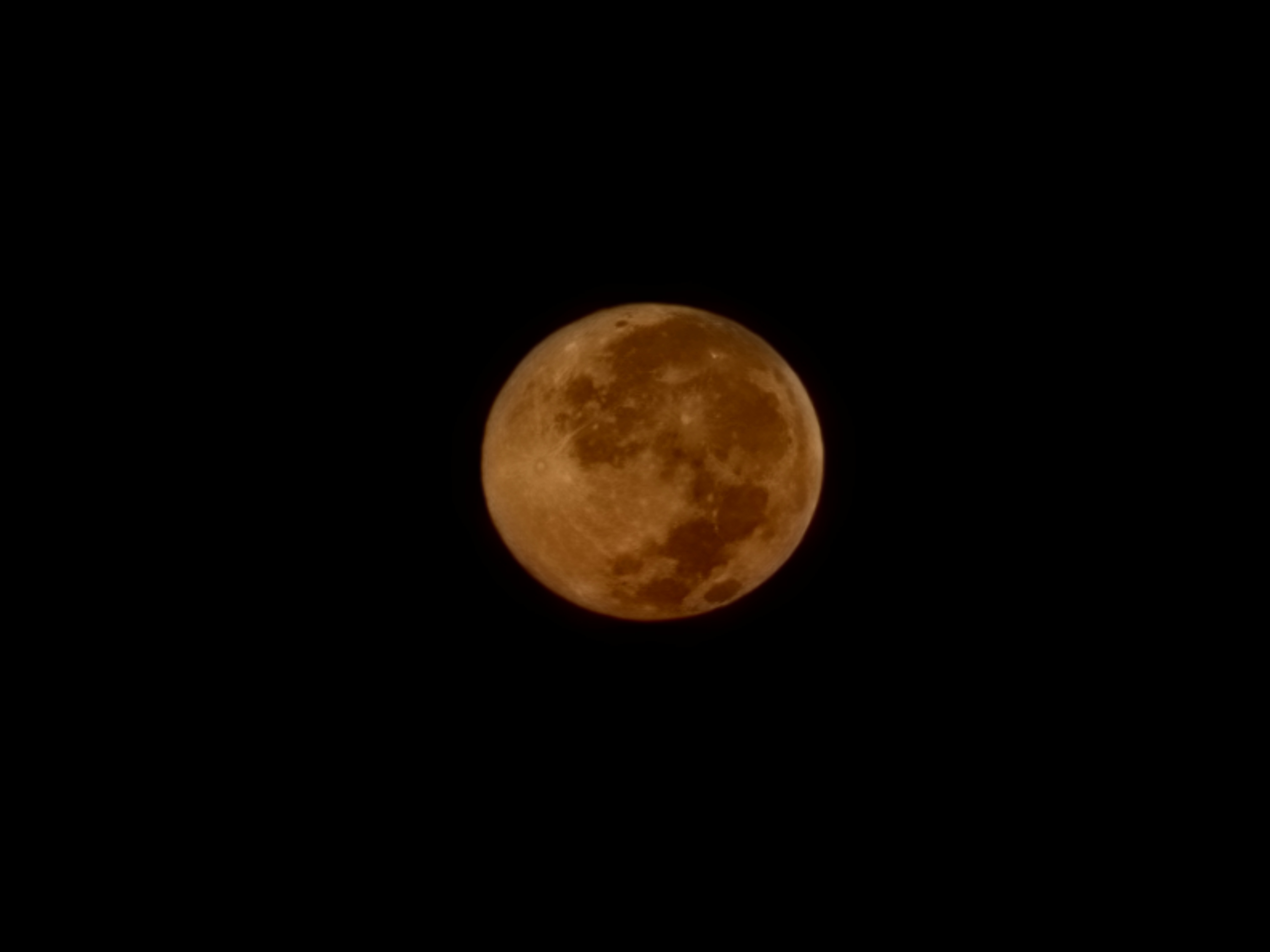 Close-up of the full harvest moon glowing deep orange against a black sky, craters and dark maria clearly visible.