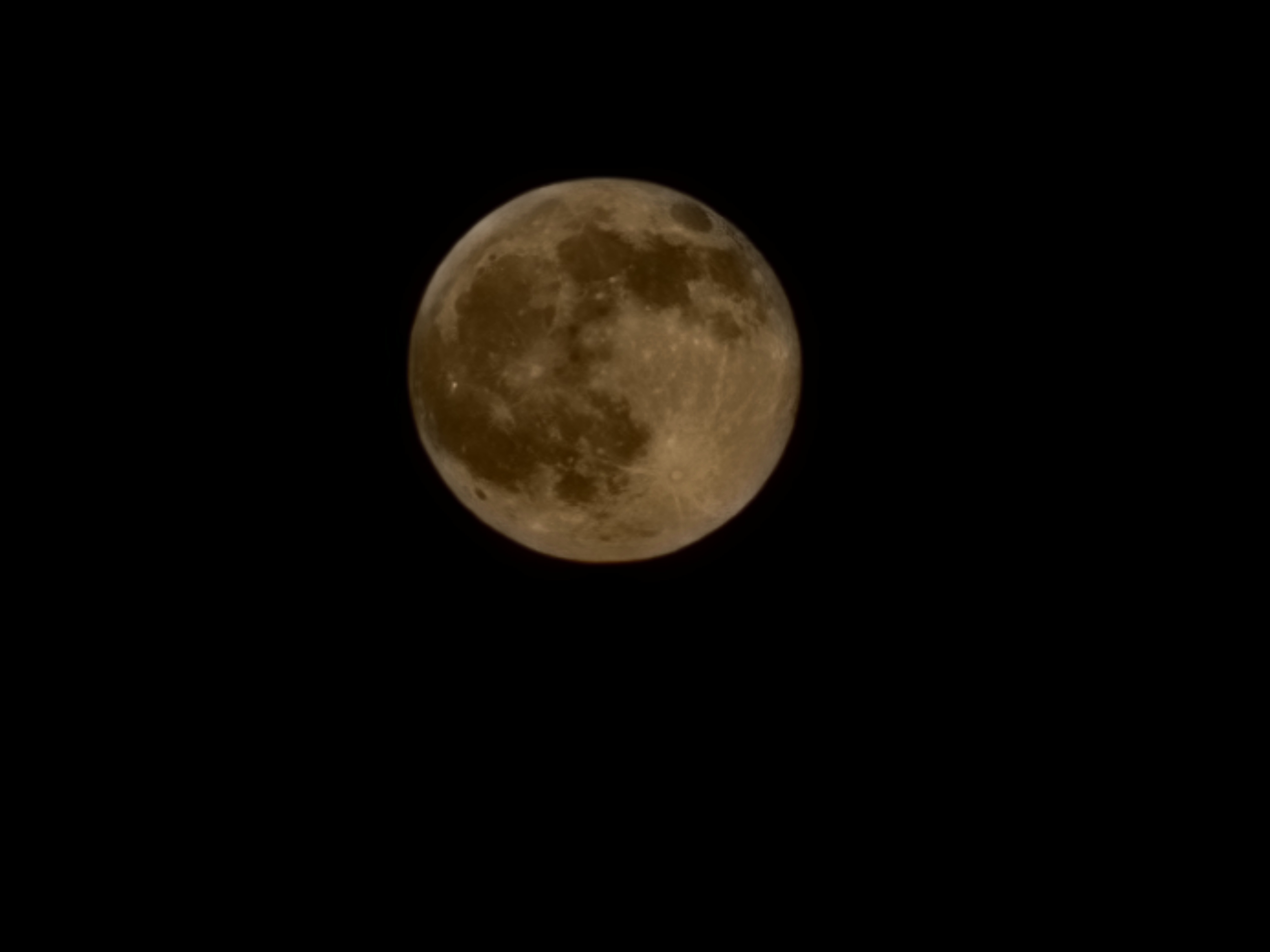 Full harvest moon glowing golden against a black sky, craters, rays and dark maria sharply visible.